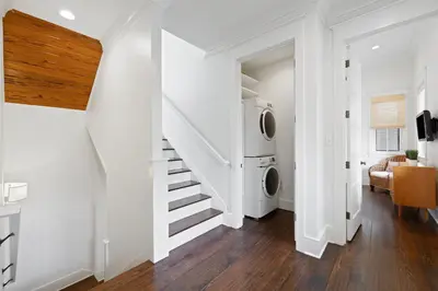 a laundry room with a staircase and a washing machine at PTO Cottage in Rosemary Beach