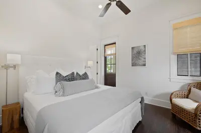 a white bedroom with a large bed and a chair at PTO Cottage in Rosemary Beach