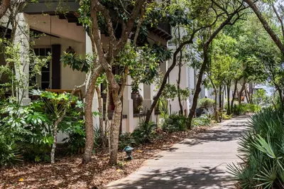a sidewalk in front of a building with trees at Belize Cottage in Rosemary Beach