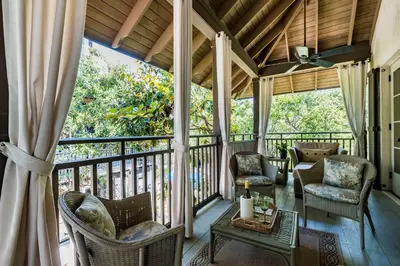 a screened in porch with chairs and a table at Belize Cottage in Rosemary Beach