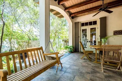 a porch with a bench and a table at Belize Cottage in Rosemary Beach