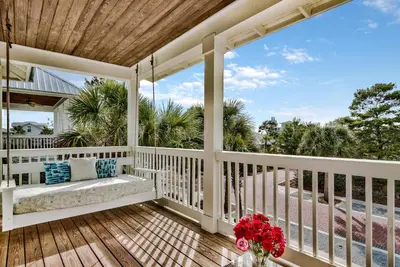 a porch with a bench and flowers on it at Turquoise Turtle in Seacrest