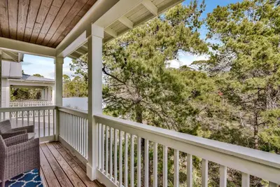 a porch with a chair and trees on it at Turquoise Turtle in Seacrest