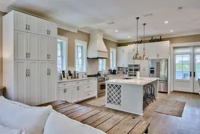 a kitchen with white cabinets and a wooden floor at Seaspell Sands in Santa Rosa Beach