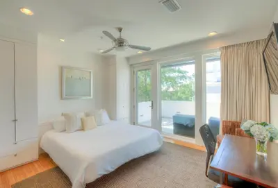 a bedroom with a bed and a desk and a window at Astley Cottage in Rosemary Beach