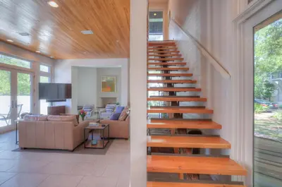 a wooden staircase in a house with a living room at Astley Cottage in Rosemary Beach