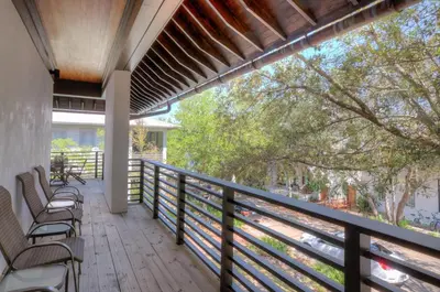 a balcony of a house with chairs and trees at Astley Cottage in Rosemary Beach