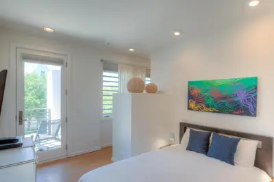 a bedroom with a bed and a painting on the wall at Astley Cottage in Rosemary Beach