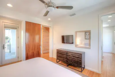 a bedroom with a bed and a tv on a wall at Astley Cottage in Rosemary Beach