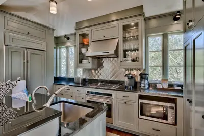 a kitchen with white cabinets and a sink at Highland Cottage in Rosemary Beach