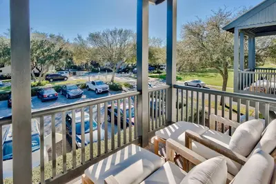 a balcony with chairs and a view of a parking lot at Highland Cottage in Rosemary Beach