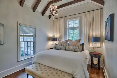 a bedroom with a large bed and two windows at Highland Cottage in Rosemary Beach