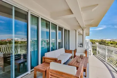 a balcony with white furniture and large windows at Legacy Alexander at Palm Court in Seacrest