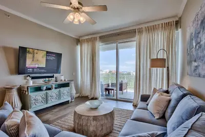 a living room with a blue couch and a tv at Legacy Alexander at Palm Court in Seacrest
