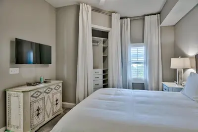a bedroom with a white bed and a tv at Legacy Alexander at Palm Court in Seacrest