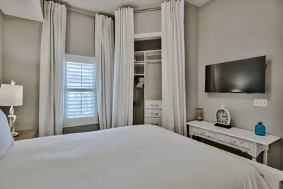 a bedroom with a white bed and a tv at Legacy Alexander at Palm Court in Seacrest