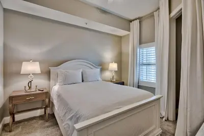 a bedroom with a white bed and a window at Legacy Alexander at Palm Court in Seacrest