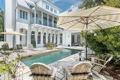 a swimming pool with two chairs and an umbrella at Carefree Cottage in Rosemary Beach