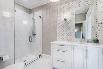 a white bathroom with a shower and a sink at Carefree Cottage in Rosemary Beach
