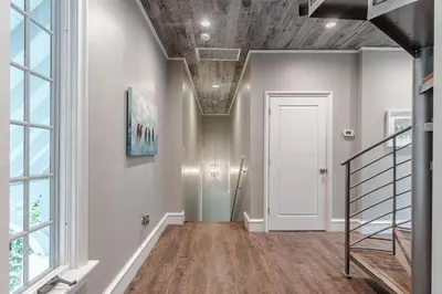 a hallway with a staircase and a white door at Carefree Cottage in Rosemary Beach