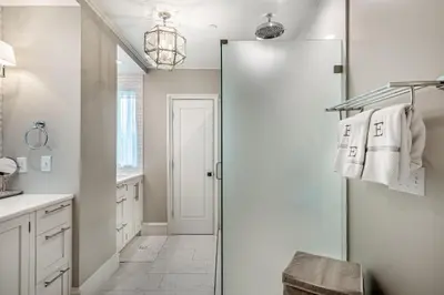 a white bathroom with a glass shower door at Carefree Cottage in Rosemary Beach