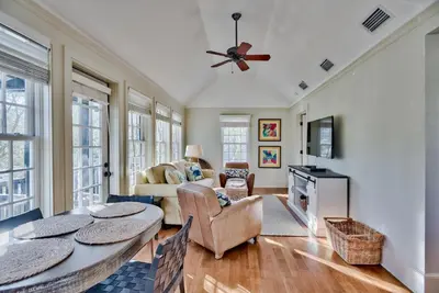 a living room with a table and a couch at Highland Carriage House in Rosemary Beach