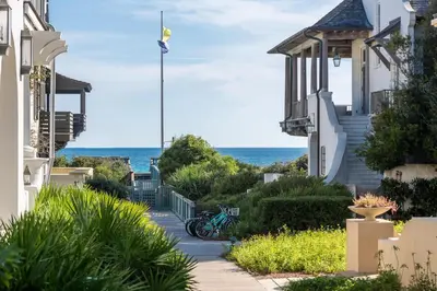 a walkway between houses with the ocean in the background at Highland Carriage House in Rosemary Beach
