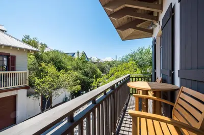 a wooden table on the balcony of a house at Belize Carriage House in Rosemary Beach
