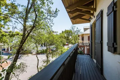 a balcony of a house with a wooden railing at Belize Carriage House in Rosemary Beach