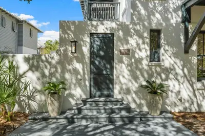 a white house with two potted plants in front of it at Acqua Cottage & Carriage House in Rosemary Beach