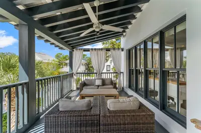 a screened porch with a couch and a table at Acqua Cottage & Carriage House in Rosemary Beach