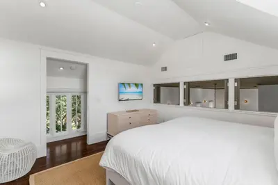 a white bedroom with a white bed and windows at Acqua Cottage & Carriage House in Rosemary Beach