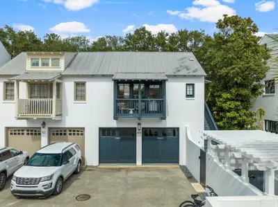 a white house with a car parked in a driveway at Acqua Cottage & Carriage House in Rosemary Beach