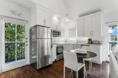 a kitchen with a stainless steel refrigerator and a table at Acqua Cottage & Carriage House in Rosemary Beach