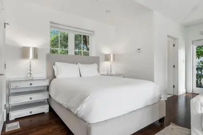 a white bedroom with a large bed and two lamps at Acqua Cottage & Carriage House in Rosemary Beach