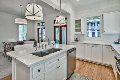 a kitchen with white cabinets and a sink at McKenzie Cottage in Rosemary Beach