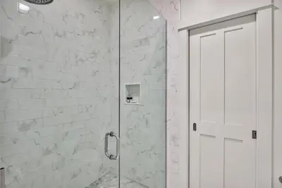 a shower with a glass door in a bathroom at McKenzie Cottage in Rosemary Beach