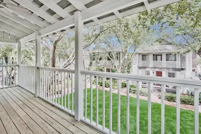 a porch with a white railing and a yard at McKenzie Cottage in Rosemary Beach