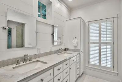 a white bathroom with two sinks and two mirrors at McKenzie Cottage in Rosemary Beach