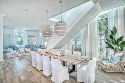 a dining room with a wooden table and white chairs at Elysee Reunion in Rosemary Beach