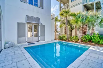 a swimming pool in the backyard of a house with palm trees at Elysee Reunion in Rosemary Beach
