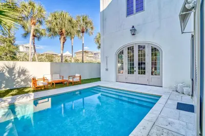 a swimming pool in the backyard of a house with palm trees at Elysee Reunion in Rosemary Beach