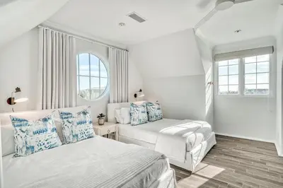 a white bedroom with two beds and a window at Elysee Reunion in Rosemary Beach
