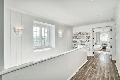 a hallway with white walls and a staircase with a window at Elysee Reunion in Rosemary Beach