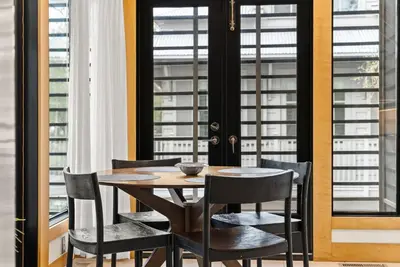 a dining room with a table and chairs and windows at Brighton Carriage House in Rosemary Beach