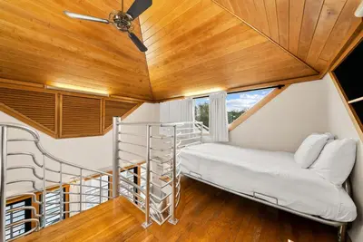 a room with a bed and a spiral staircase at Brighton Carriage House in Rosemary Beach