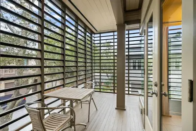 a balcony with a table and chairs and windows at Brighton Carriage House in Rosemary Beach