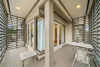 a screened porch with a bench and windows at Brighton Carriage House in Rosemary Beach