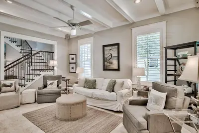 a living room with white furniture and a staircase at Sylvia's Cottage in Rosemary Beach
