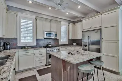 a kitchen with white cabinets and a island with stools at Sylvia's Cottage in Rosemary Beach
